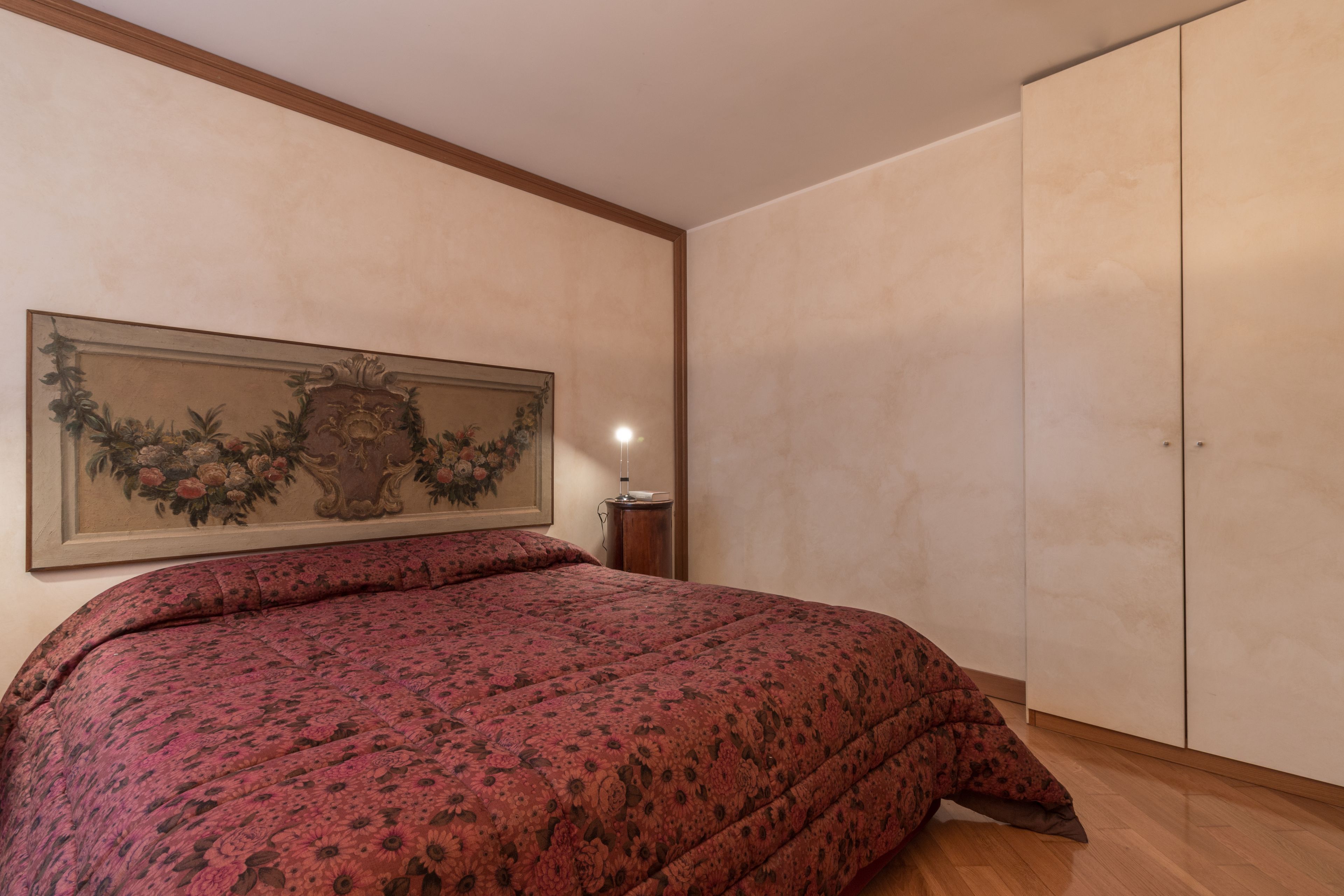 Une chambre à coucher avec un grand lit, une armoire et une œuvre d’art encadrée accrochée au mur.