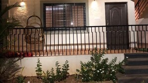 Una casa de dos pisos con un porche delantero, un portón de metal negro y una ventana con rejas.