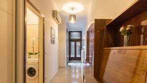 A hallway with a washing machine, a wooden cabinet, and a vase with flowers. - Rialto Bridge Venetian Style (Venice)