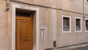 A beige building with a wooden door, a number plate, and barred windows. - Rialto Bridge Venetian Style (Venice)