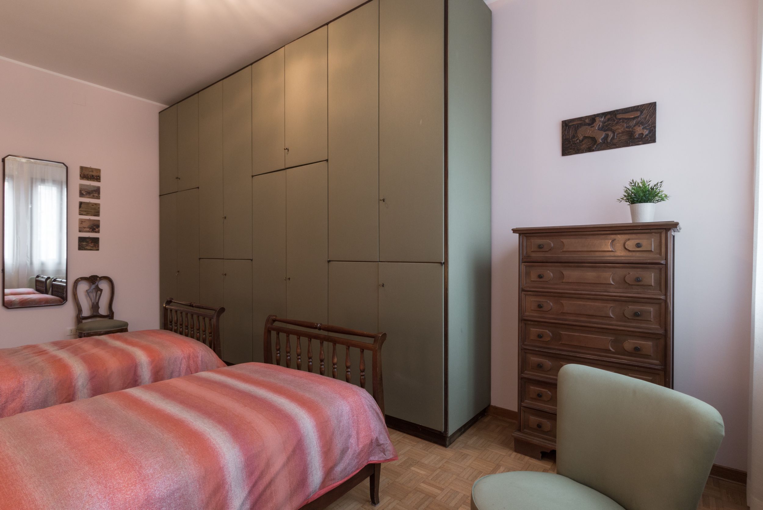 A bedroom with two beds, a dresser, a chair, and a wardrobe.