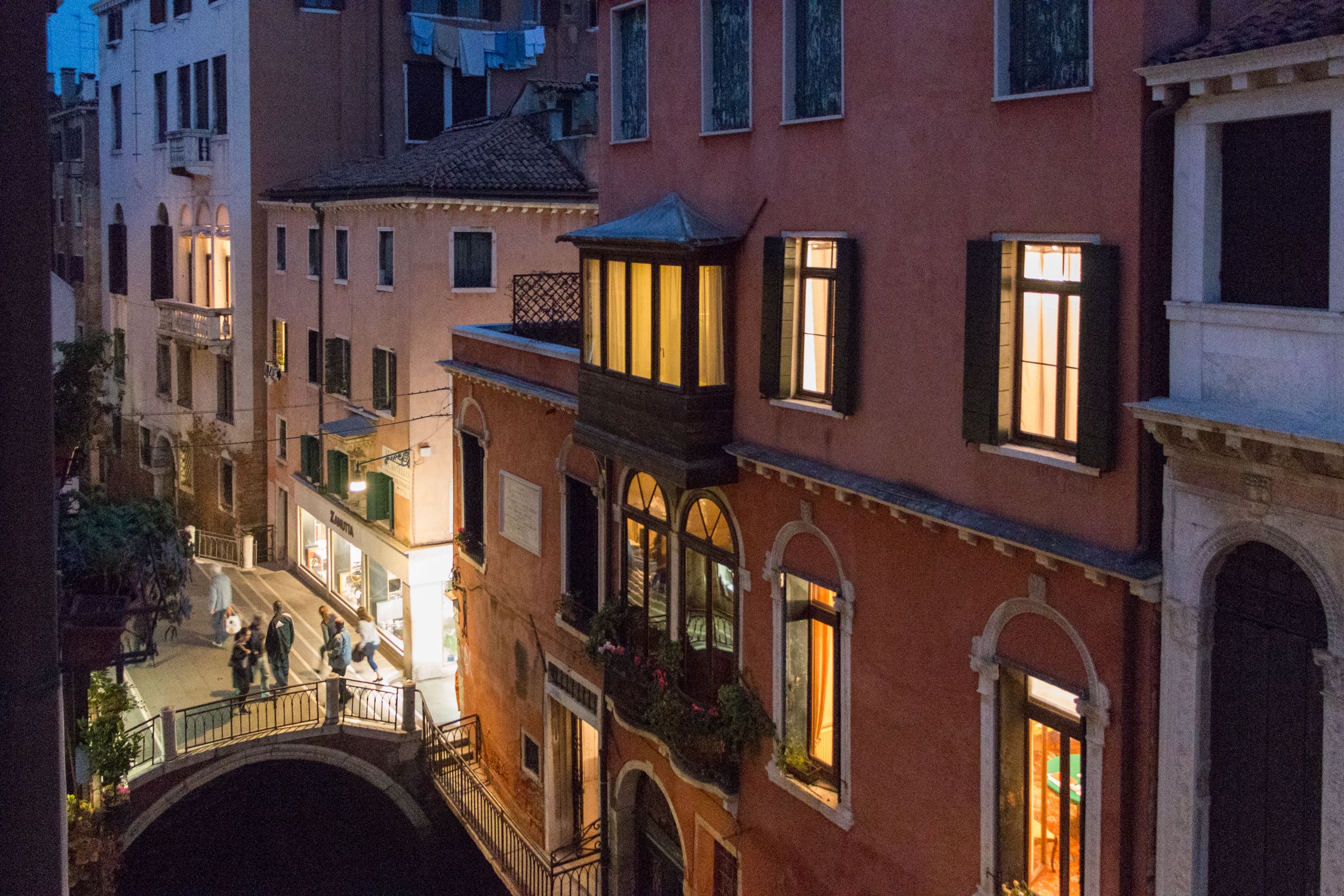 A narrow street with buildings on either side, a pedestrian bridge, and a canal.