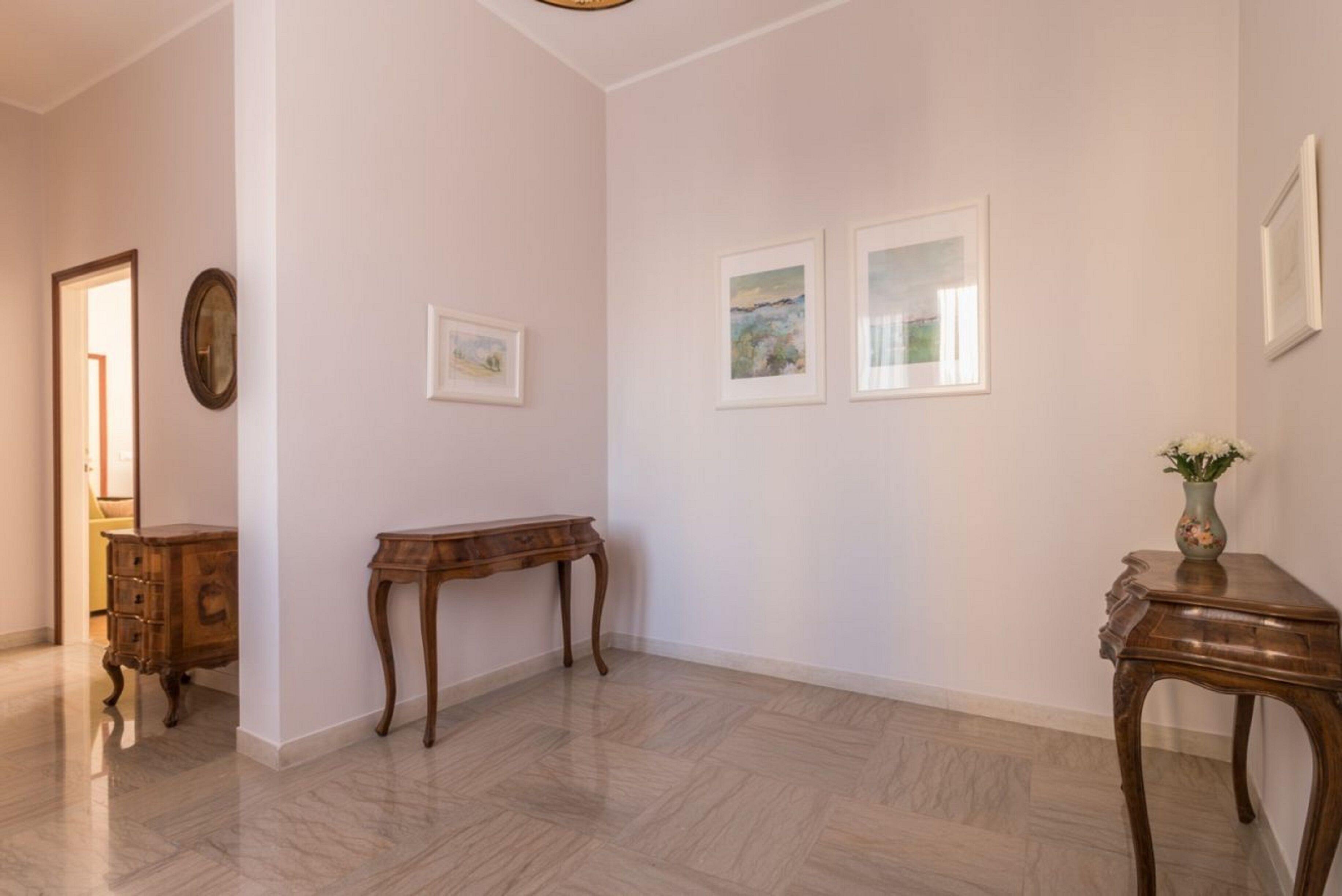 Ein Flur mit einer hölzernen Bank, einem kleinen Tisch mit einer Vase und gerahmten Bildern an der Wand.