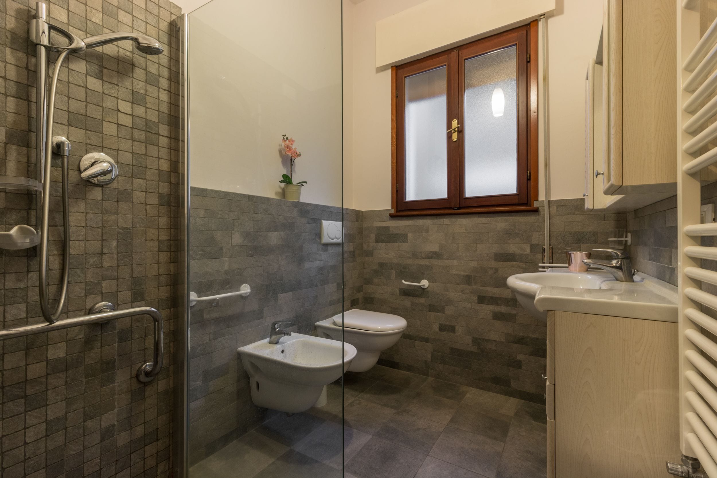 Une salle de bain avec une douche à parois de verre, un bidet, des toilettes et un lavabo.