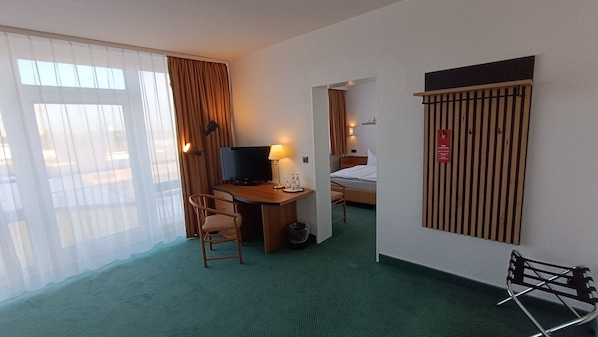 Habitación de hotel con escritorio, silla, cama y vista por la ventana.