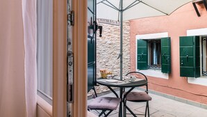 An outdoor patio with a table and chairs, a stone wall, and a door with a sign. - Cà Lessia (Venice)