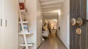 A hallway with a white ladder bookshelf, a dark wooden door, and a white chair in the background. - Cà Lessia (Venice)