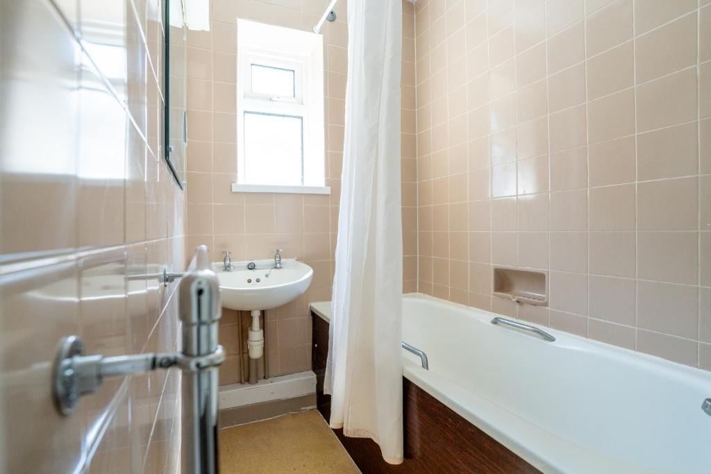 A bathroom with a bathtub, a sink, and a window.