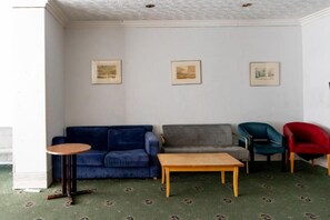A living room with a blue sofa, a grey sofa, a wooden coffee table, and two chairs. - Norwich Central Hotel - Near Norwich Train Station & Carrow Road Stadium (Norwich)