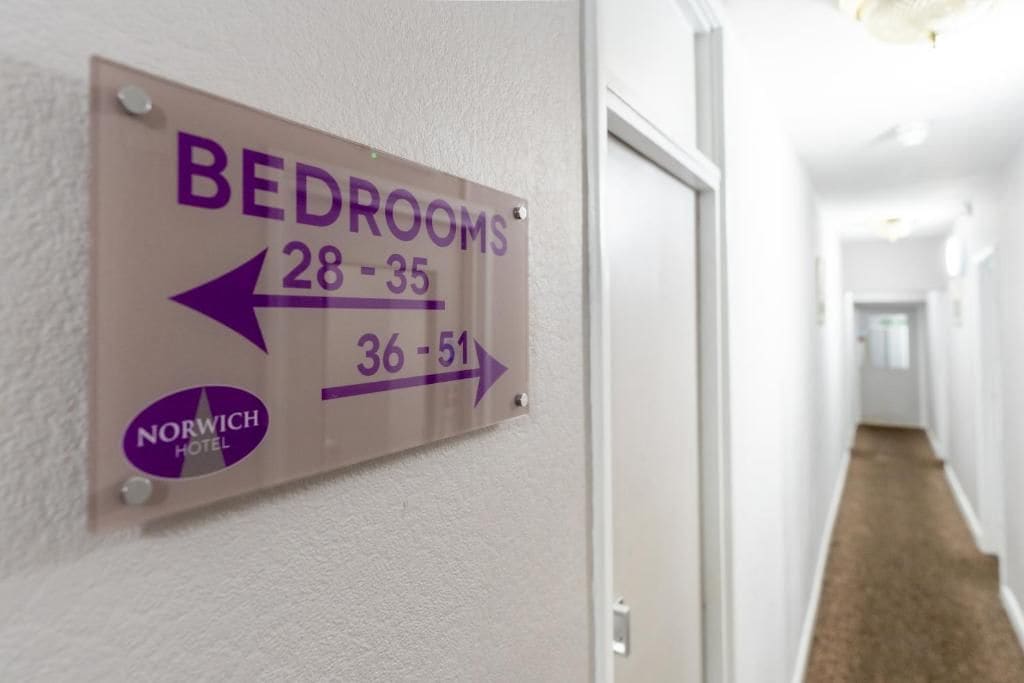 A directional sign for hotel bedrooms with arrows pointing to different room numbers.