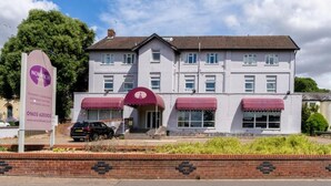 A two-story hotel with a red awning over the entrance, a brick wall in front, and a clear sky. - Norwich Central Hotel - Near Norwich Train Station & Carrow Road Stadium (Norwich)