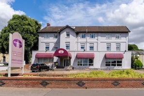 A two-story hotel with a red awning over the entrance, a brick wall in front, and a clear sky. - Norwich Central Hotel - Near Norwich Train Station & Carrow Road Stadium (Norwich)