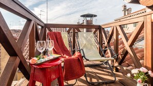 A wooden deck with a table set for two, featuring wine glasses, a rose, and a menu. - Rialto Rooftop Terrace Loft (Venice)