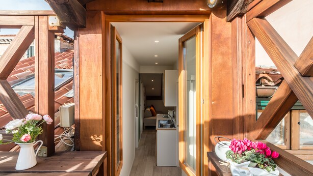 A narrow wooden corridor leading to a room with a kitchenette and a sofa. - Rialto Rooftop Terrace Loft (Venice)