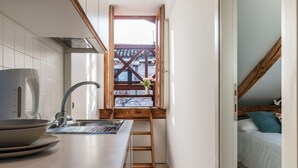 A compact kitchen with a built-in stove, a sink, and a window overlooking a brick building. - Rialto Rooftop Terrace Loft (Venice)