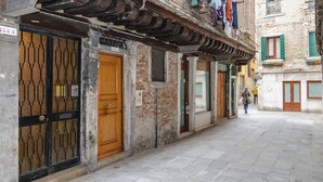 A narrow street with traditional buildings, wooden doors, and a cobblestone path. - Rialto Rooftop Terrace Loft (Venice)