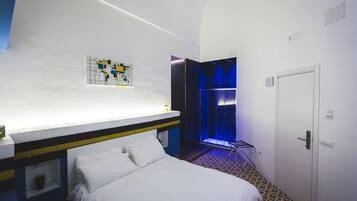 Hotellihuone, jossa on sänky, suihkutila ja seinälle kiinnitetty taideteos.
