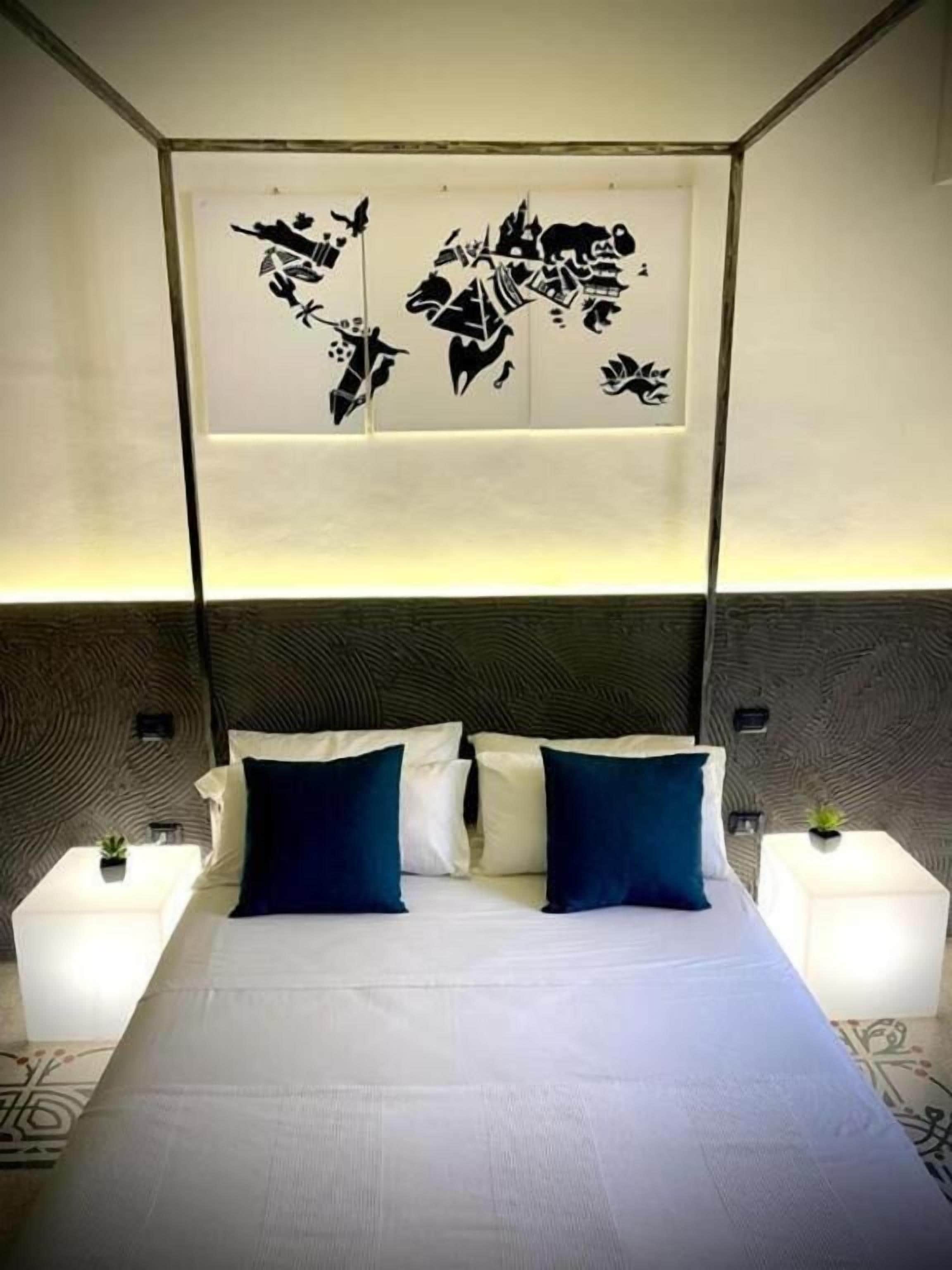 A modern hotel room with a large bed, two nightstands, and a unique wall art piece above the bed.