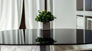 A round glass table with a small potted plant in the center, surrounded by beige chairs. - Casa Manfredi B&B (Manfredonia)