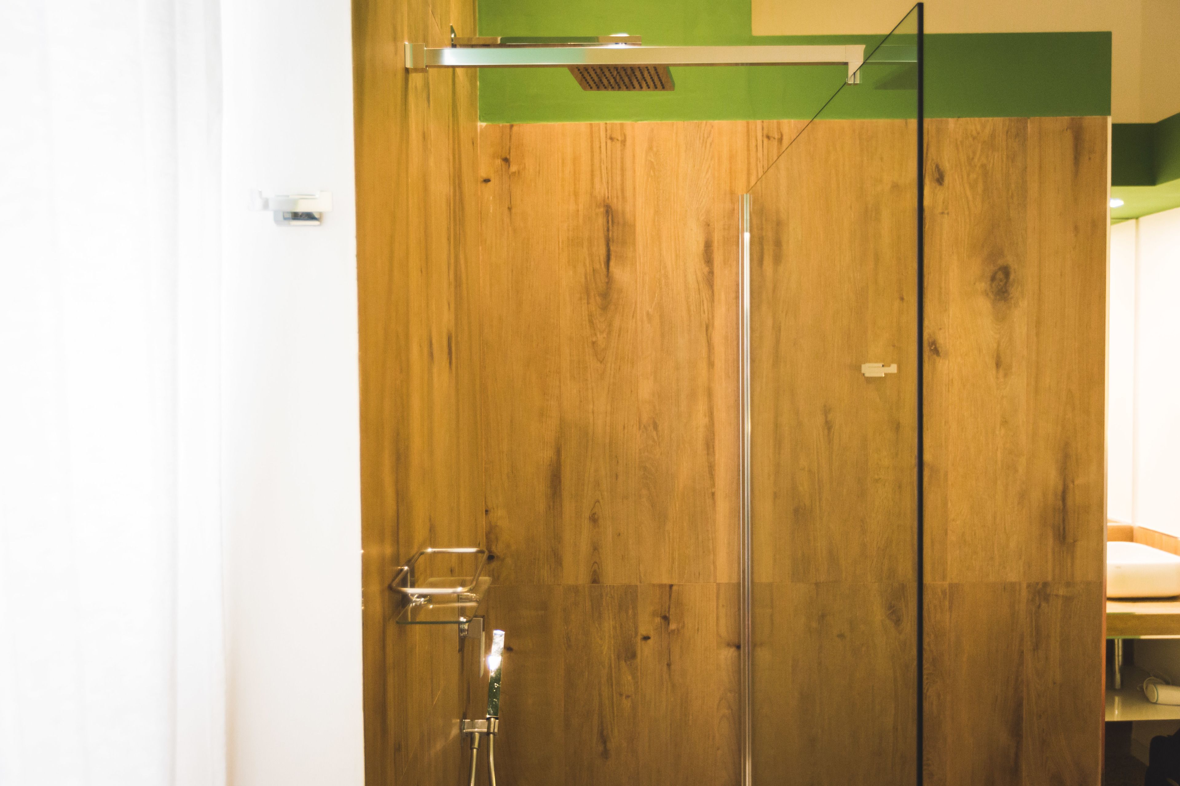 A wooden door with a glass panel, a metal handle, and a small shelf with a bottle.