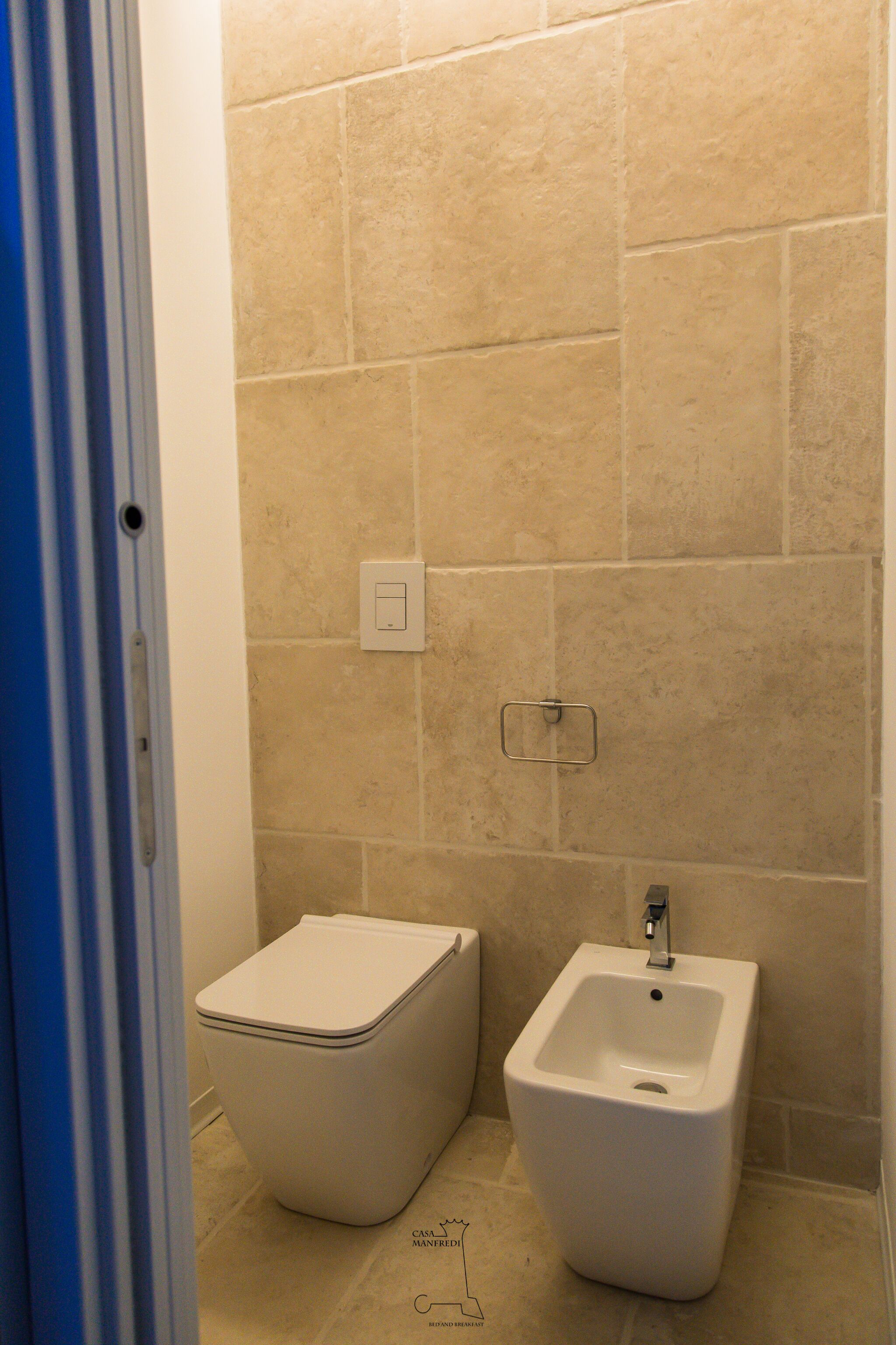 A bathroom with beige tiles, a toilet, and a bidet.