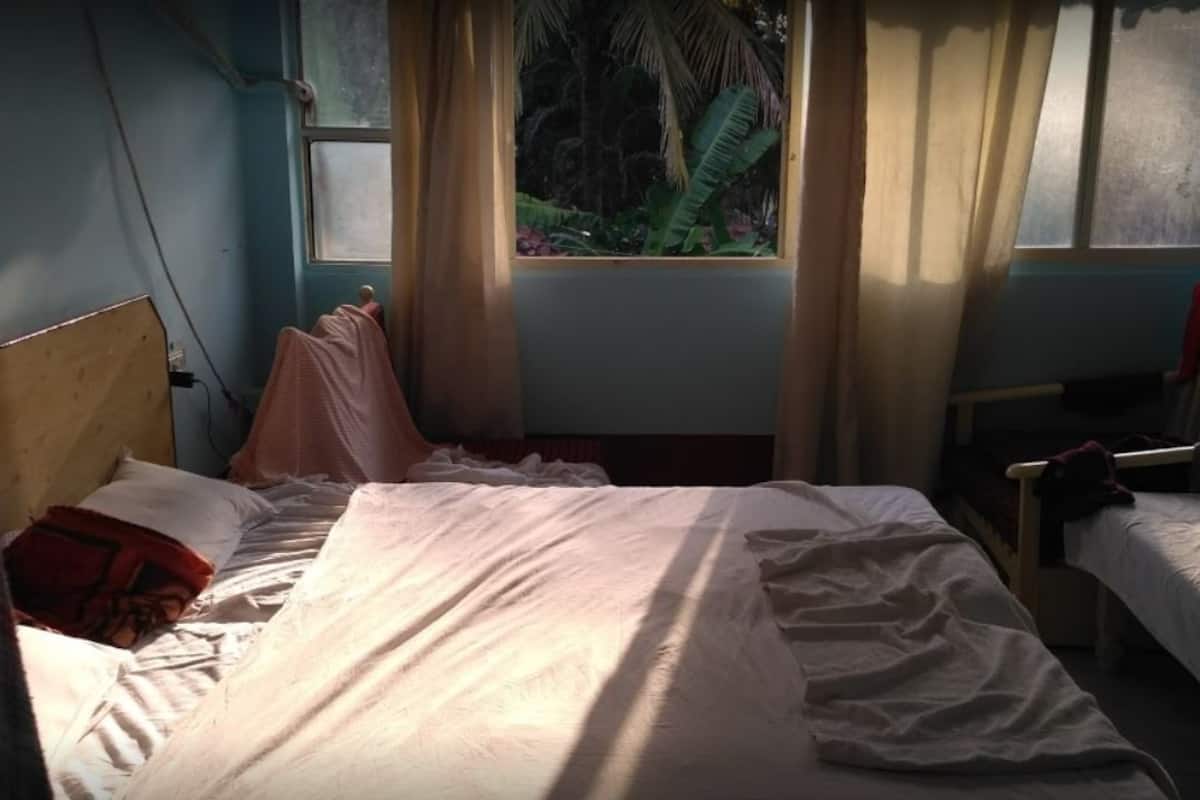 Habitación con dos camas, una ventana con cortinas y vistas a zonas verdes.