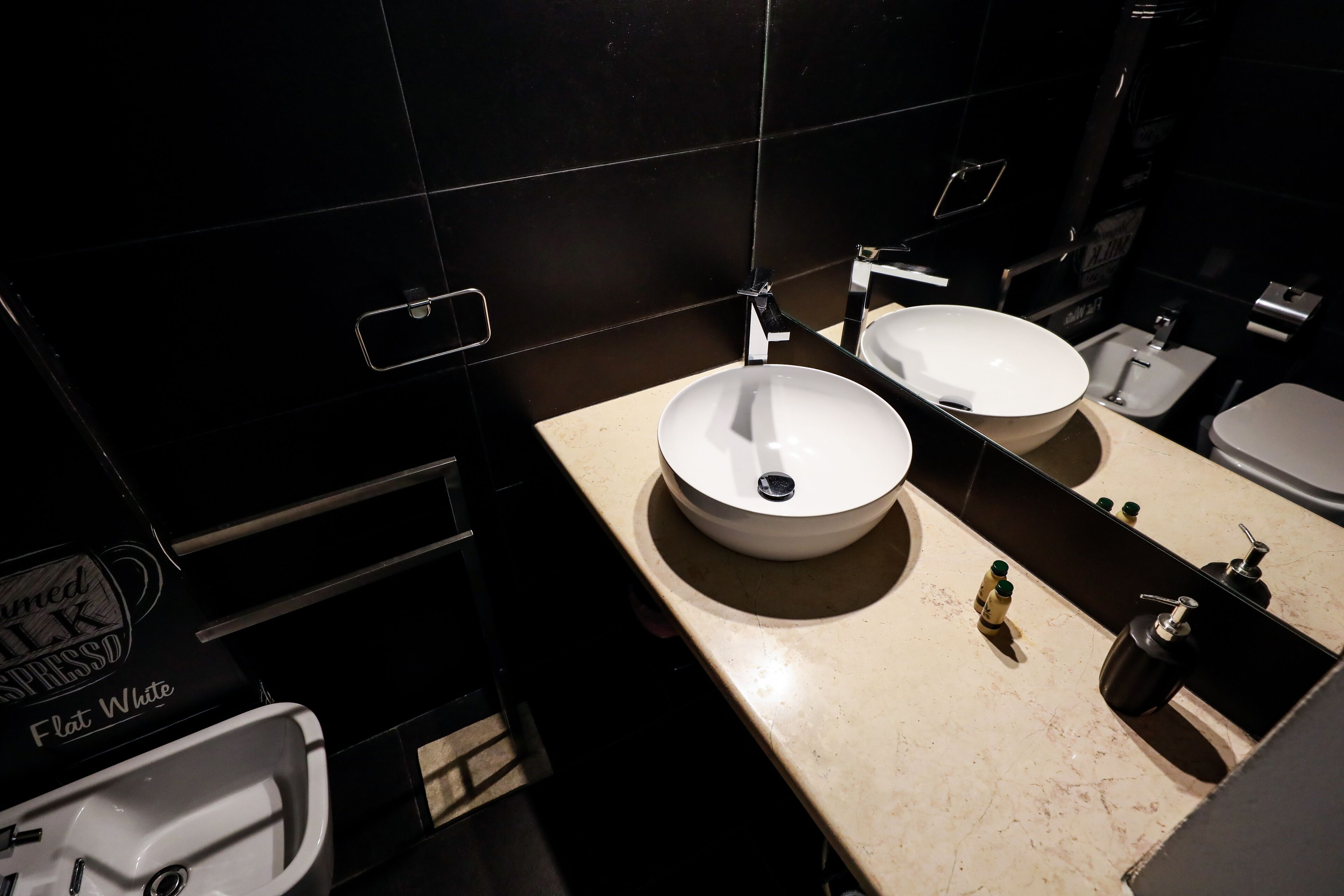 A modern bathroom with two sinks, a mirror, and a toilet.