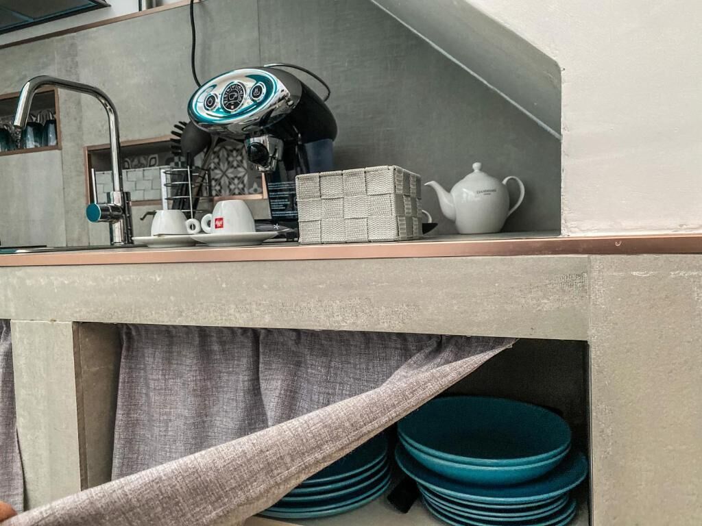 A kitchen area with a coffee machine, a kettle, and stacked plates.