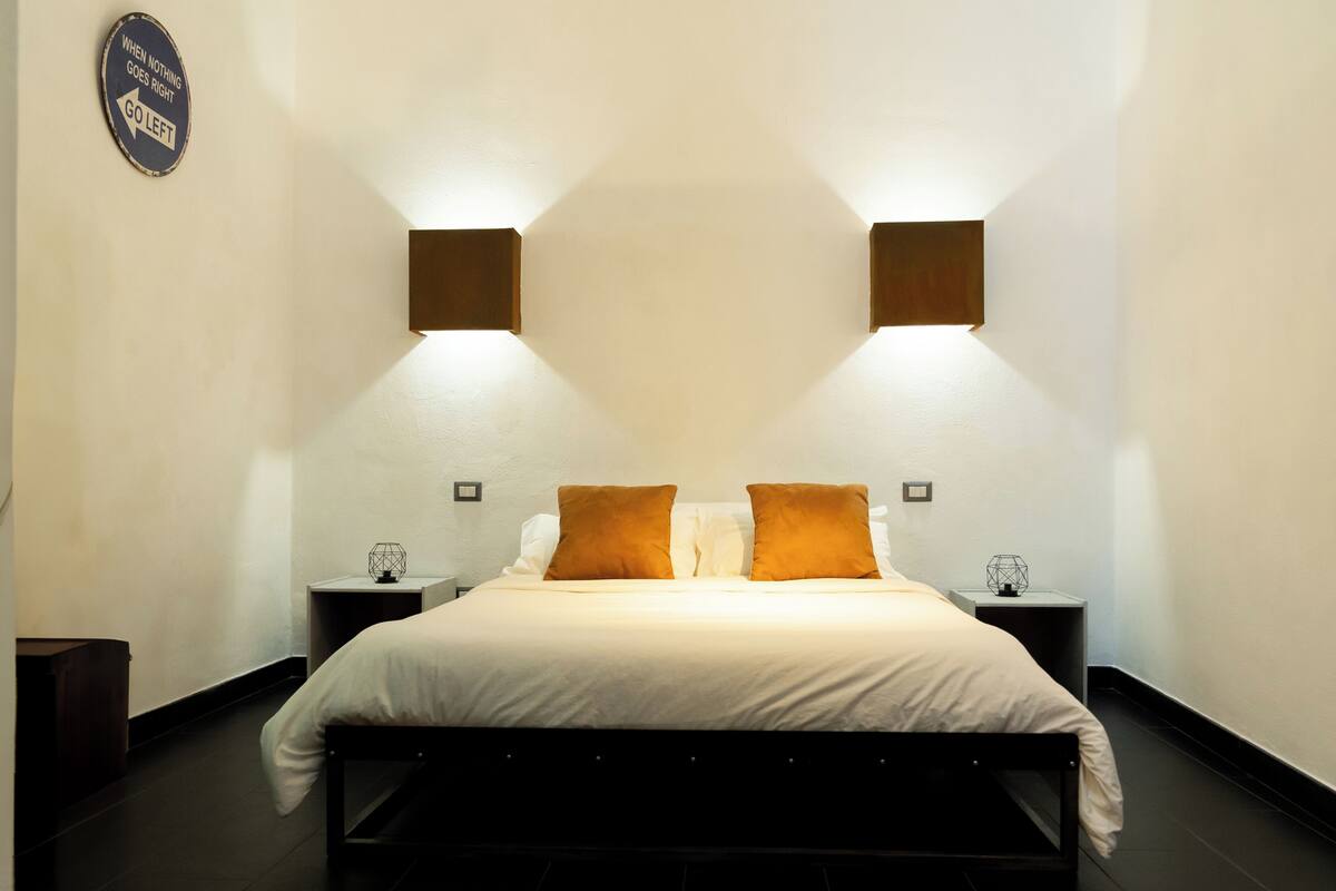 Une chambre à coucher avec un lit, deux tables de chevet et un panneau fixé au mur.
