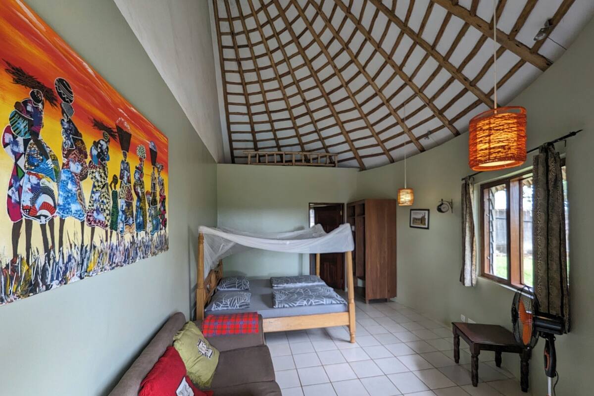 Una habitación con una cama litera, un sofá, un cuadro en la pared y una ventana con cortinas.