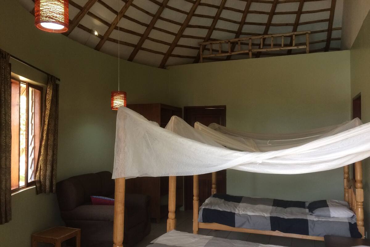 Una habitación con cama, una mesita y una ventana con cortinas.