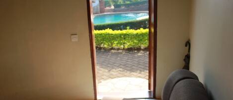 Habitación con vista a una piscina y jardín a través de un ventanal.