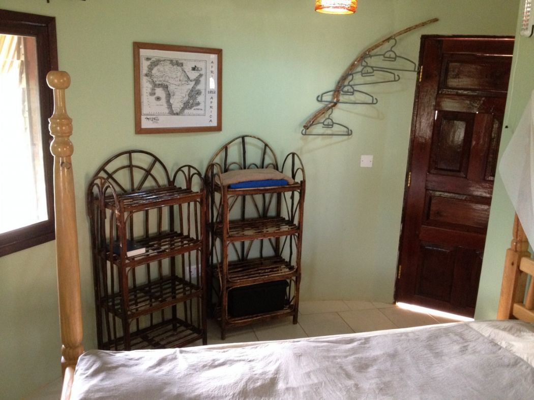 Une pièce avec un lit, deux étagères en métal, une porte en bois et une carte encadrée accrochée au mur.