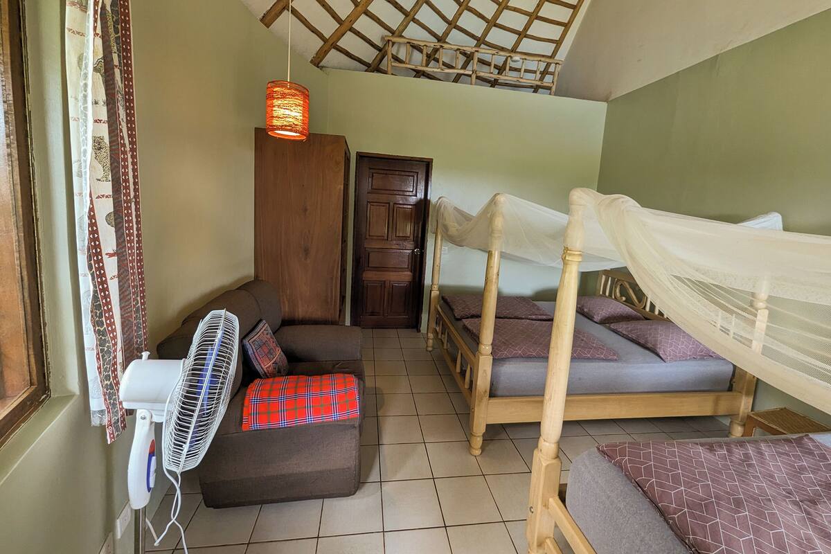 Una habitación con cama, sofá, ventilador y armario de madera.