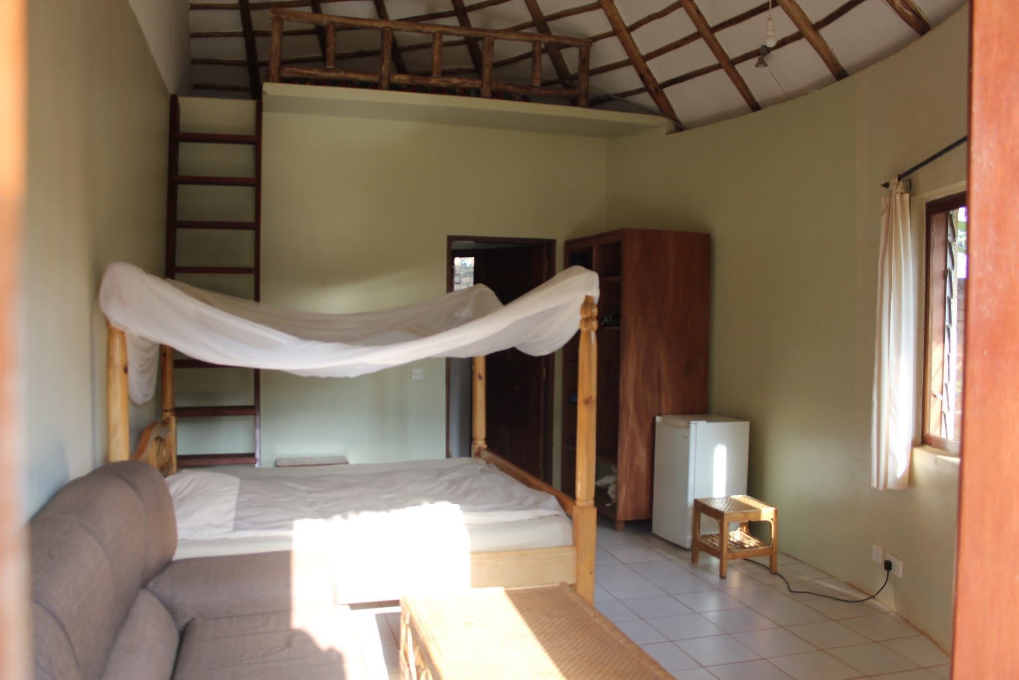 A bedroom with a bunk bed, a small table, a TV, and a ladder.