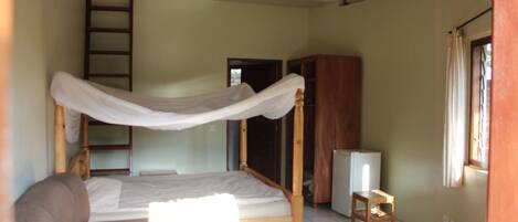 A bedroom with a bunk bed, a small table, a TV, and a ladder.
