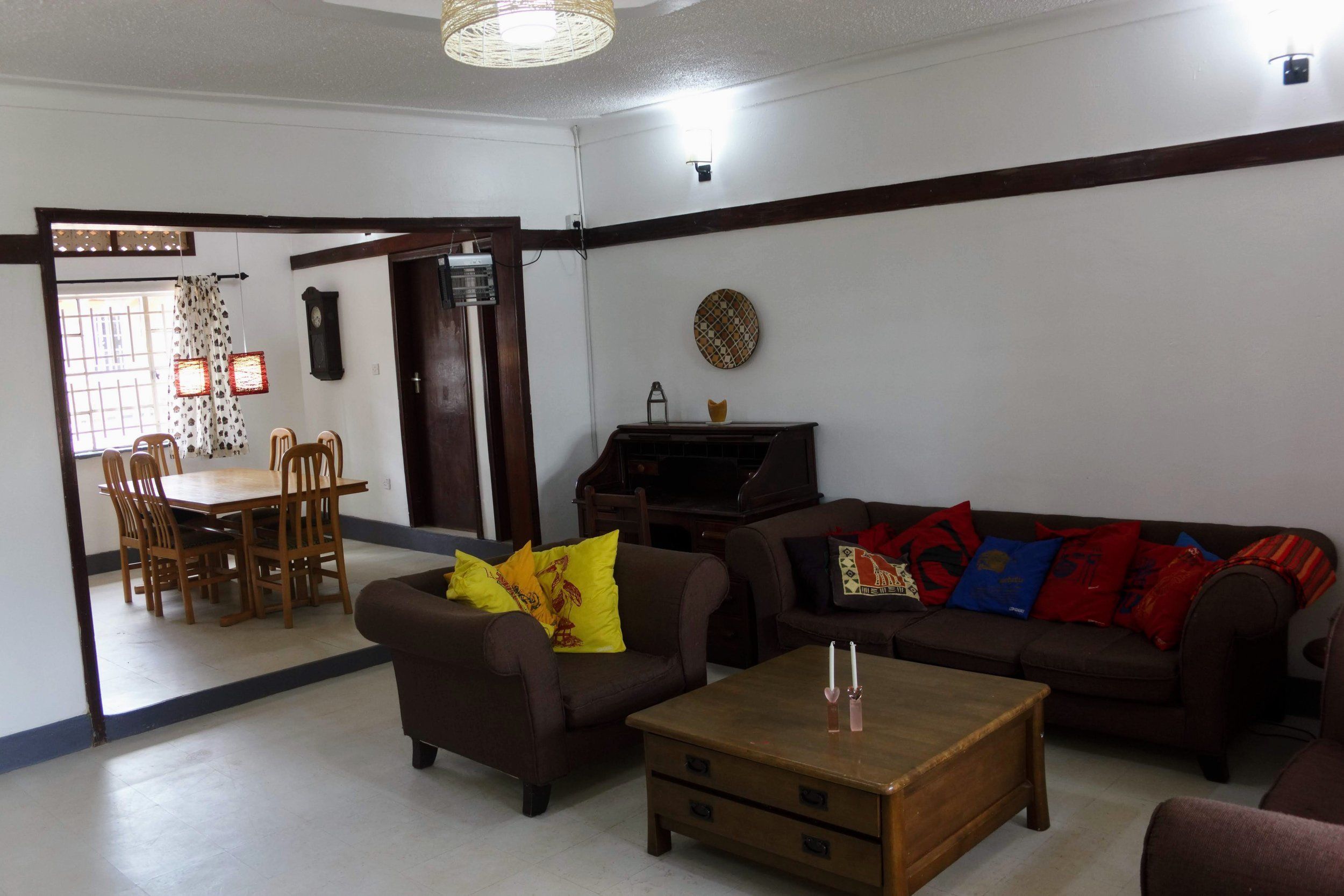 A living room with a brown sofa, a wooden coffee table, and a dining area with a wooden table and chairs.