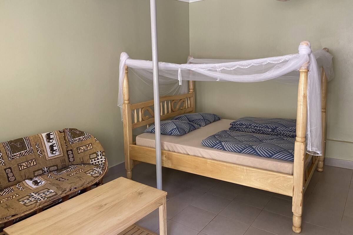 Una habitación con una cama de madera con dosel, un sofá estampado y una pequeña mesa.