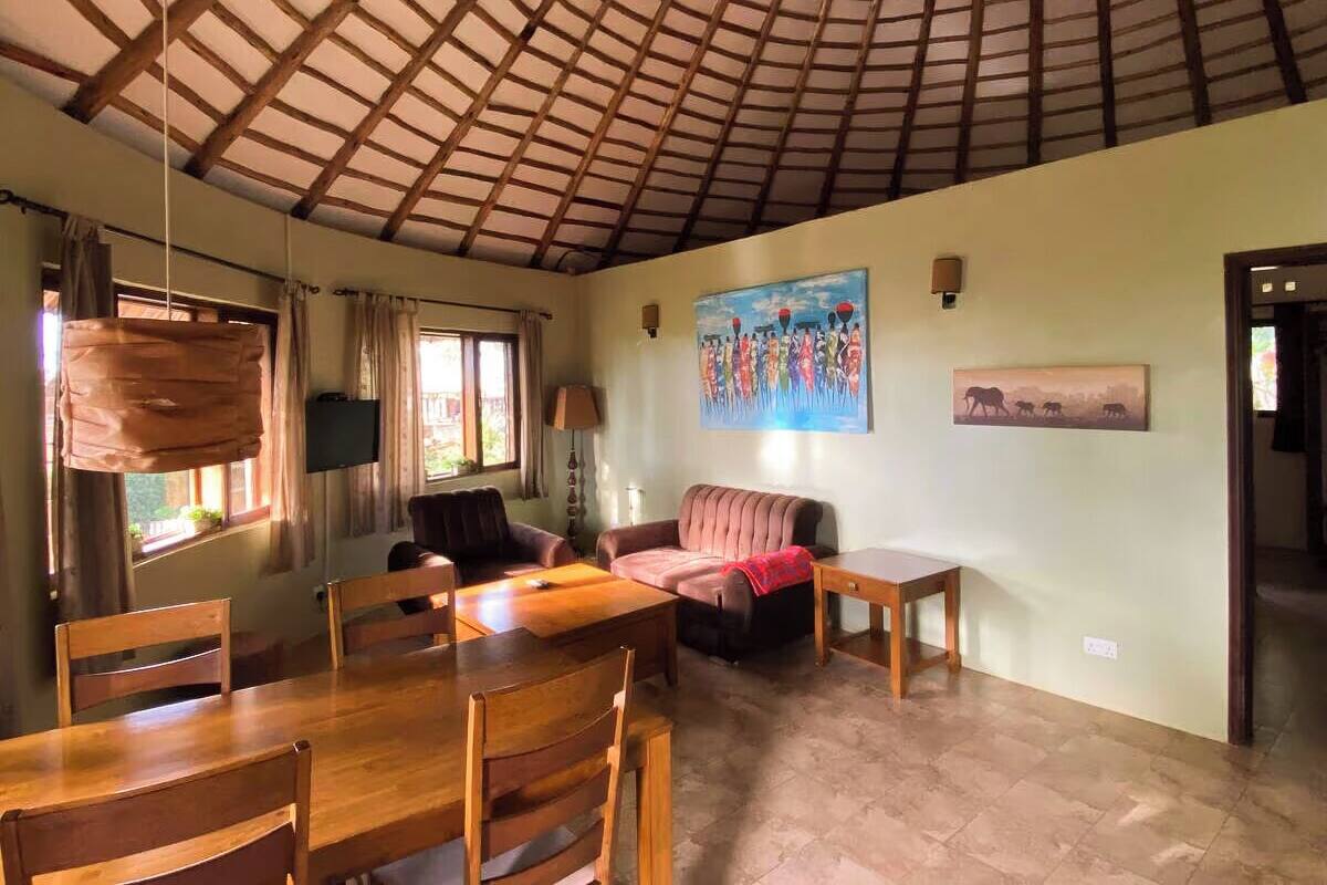 Una habitación amplia con techo alto, un comedor con muebles de madera, un sofá y un cuadro en la pared.