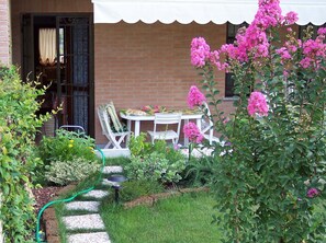 Ein Garten mit Tisch und Stühlen, einer Ziegelmauer und einem weißen Markisenvorzelt.