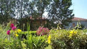 A garden with various flowers and a building in the background. - B&B Il Parco (Parma)