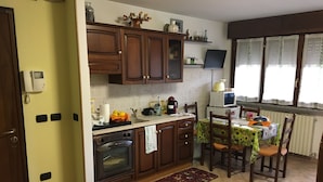 A kitchen with wooden cabinets, a microwave, a coffee maker, and a dining table with chairs. - B&B Il Parco (Parma)