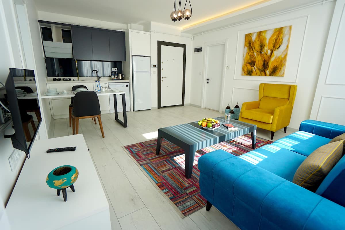 Ein modernes Wohnzimmer mit einem blauen Sofa, einem gelben Sessel und einem Essbereich mit Tisch und Stühlen.