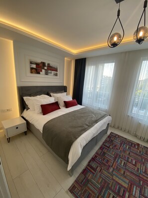 A modern bedroom with a large bed, a nightstand, a patterned rug, and a ceiling light fixture. - Viva Suites Cappadocia (Nevsehir)