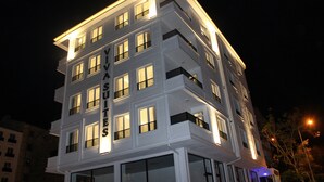 Un hotel de varios pisos con ventanas y balcones iluminados, que presenta un diseño arquitectónico moderno.
