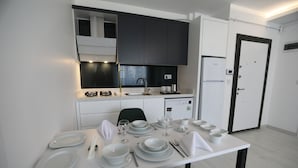 Una cocina moderna con armarios blancos, una mesa de comedor preparada para cuatro personas y un refrigerador.