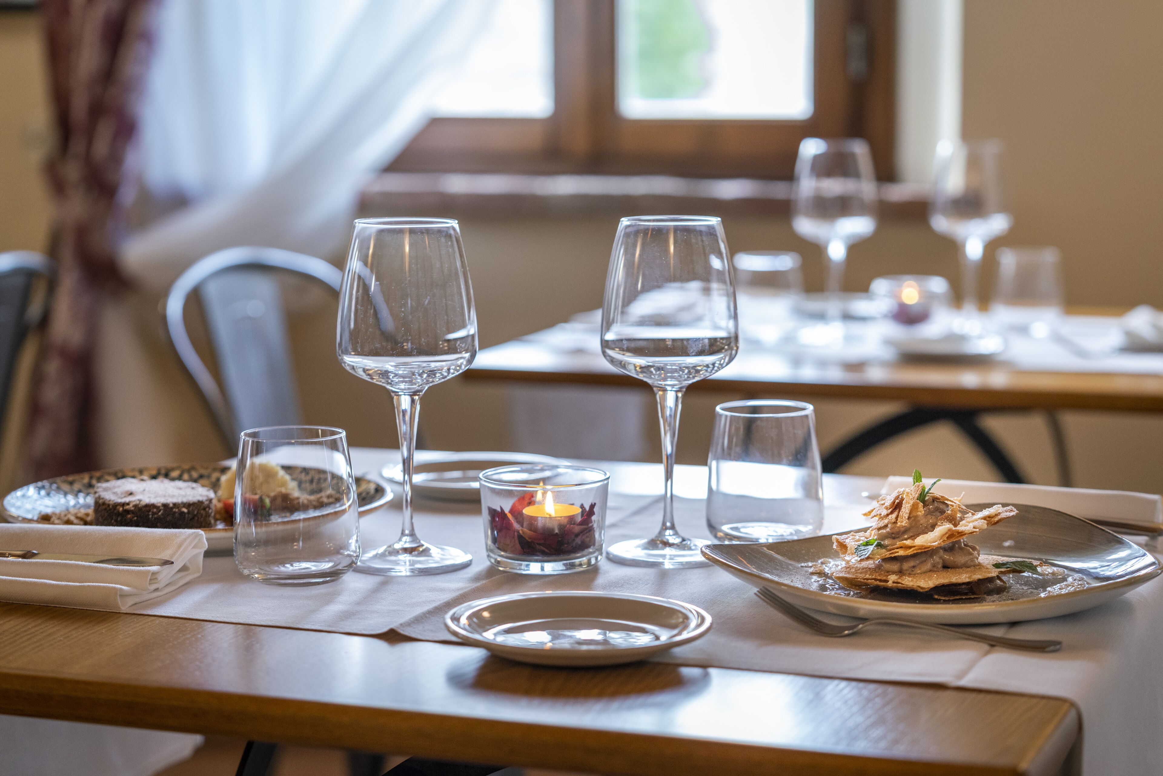Una mesa lista con platos, vasos y una vela.