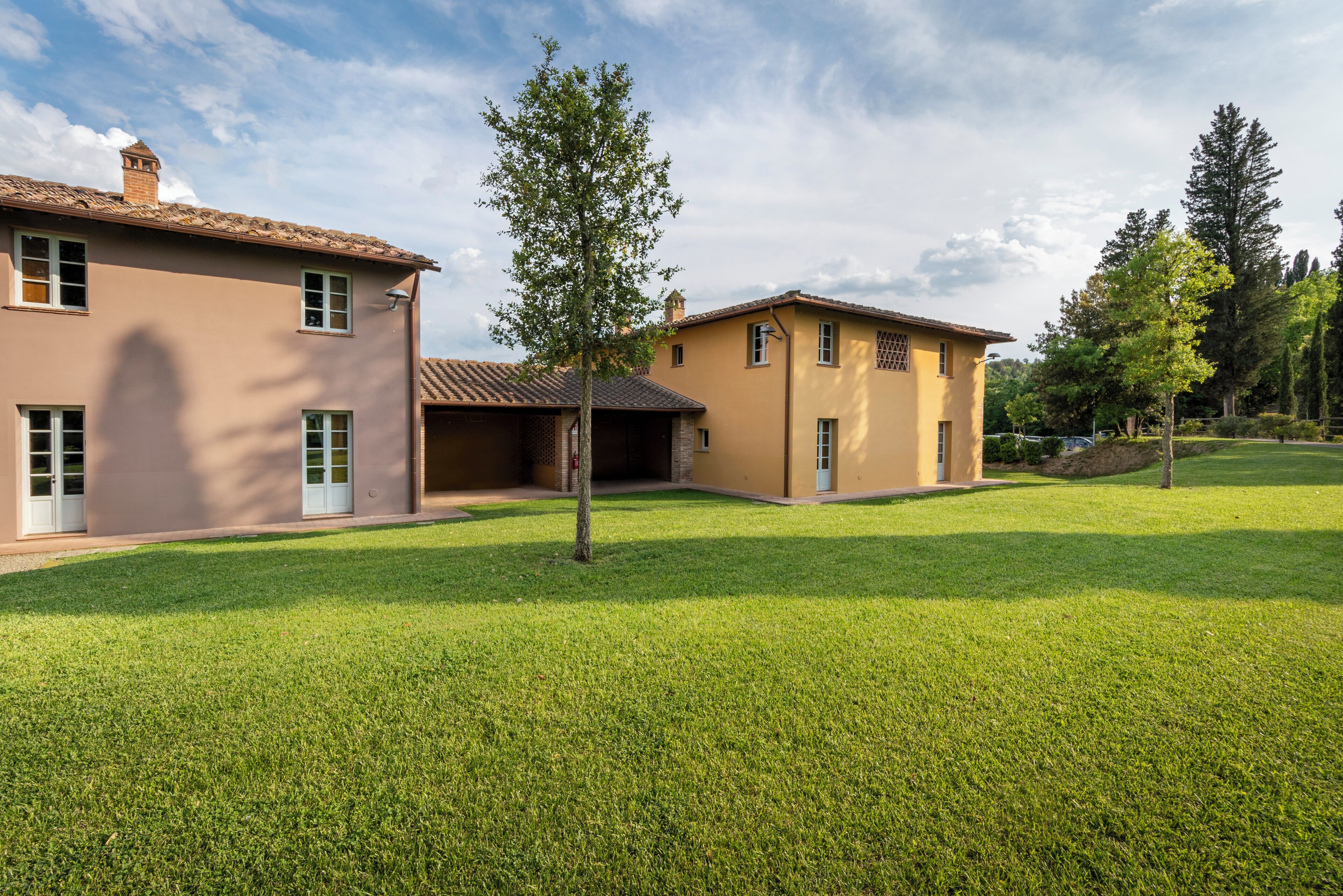 A residential property with a well-maintained lawn, a patio area, and a two-story building with a tiled roof.