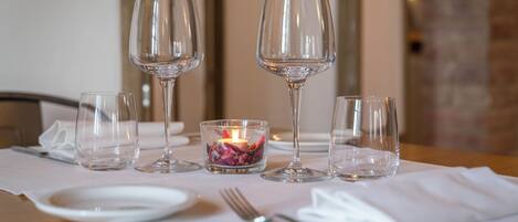 Una mesa servida con copas de vino, una vela y un tenedor.