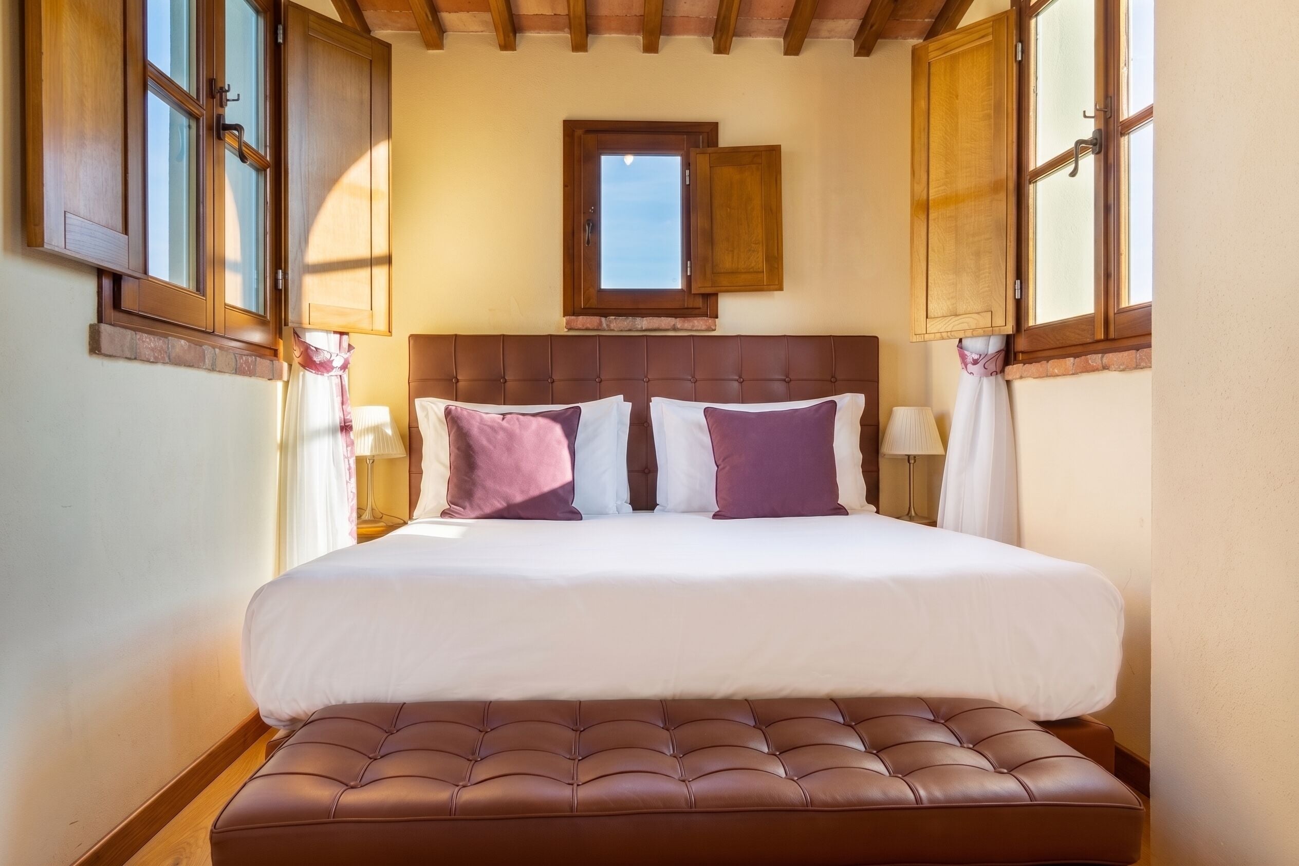 A bedroom with a large bed, a headboard, and two bedside lamps.